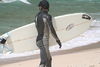 Surfer in wetsuit carries his surboard on the beach.JPG